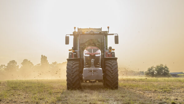 Front view of Massey Ferguson 9S Series tractor working in a dusty field at sunrise
