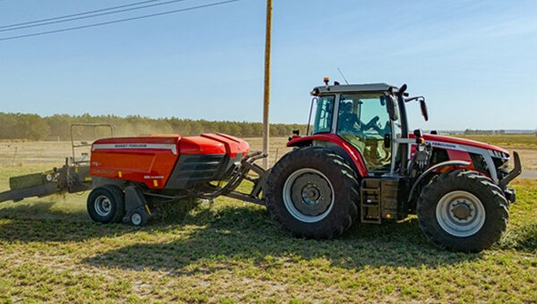 Hesston by Massey Ferguson SB.1436DB small square baler connected to a tractor, capturing the side profile during hay baling on a sunny day.