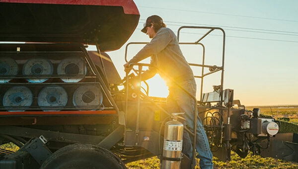 Farmer inspecting the twine capacity of a Hesston by Massey Ferguson SB.1436DB small square baler, ensuring efficient baling performance in the field.