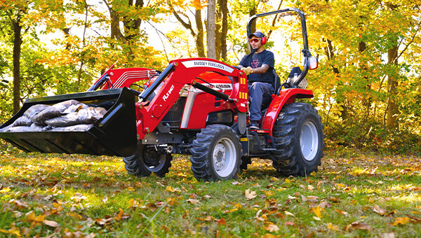 Massey Ferguson 1E Series compact tractor with a front loader bucket, ideal for hauling, digging, and material handling in various agricultural and landscaping applications.