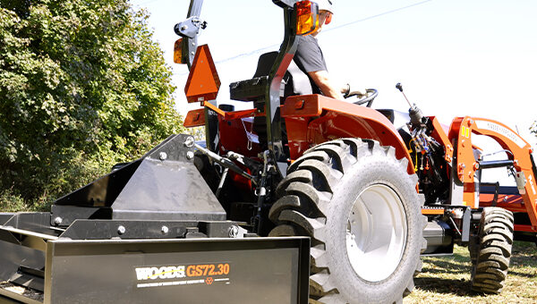 Massey Ferguson 1E Series compact tractor equipped with a Woods box blade for efficient grading, leveling, and material moving in tough terrain.