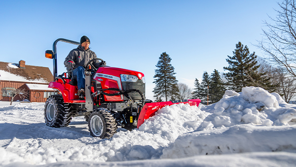 Massey Ferguson 1GC Series sub-compact tractor using a front-mounted snow blade to efficiently clear driveways and pathways during winter.