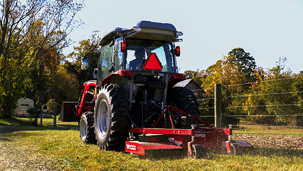 Massey Ferguson 1M Series compact tractor rear view, equipped with a rotary cutter for efficient field and pasture maintenance.