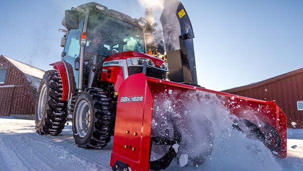 Massey Ferguson 1M Series compact tractor equipped with a heavy-duty snow blower, clearing deep snow in cold winter conditions for maximum efficiency.
